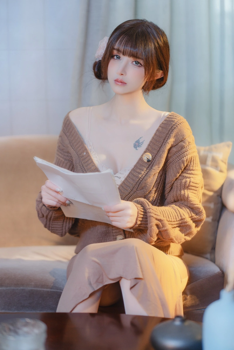 鹿八岁手持一叠纸，坐在棕色沙发上，咖啡色毛衣微微敞开露出内搭蕾丝，神色端庄优雅。
